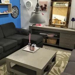 Ingerichte woonkamer met zwarte bank, grijze tv-meubel, spiegel en decoratie