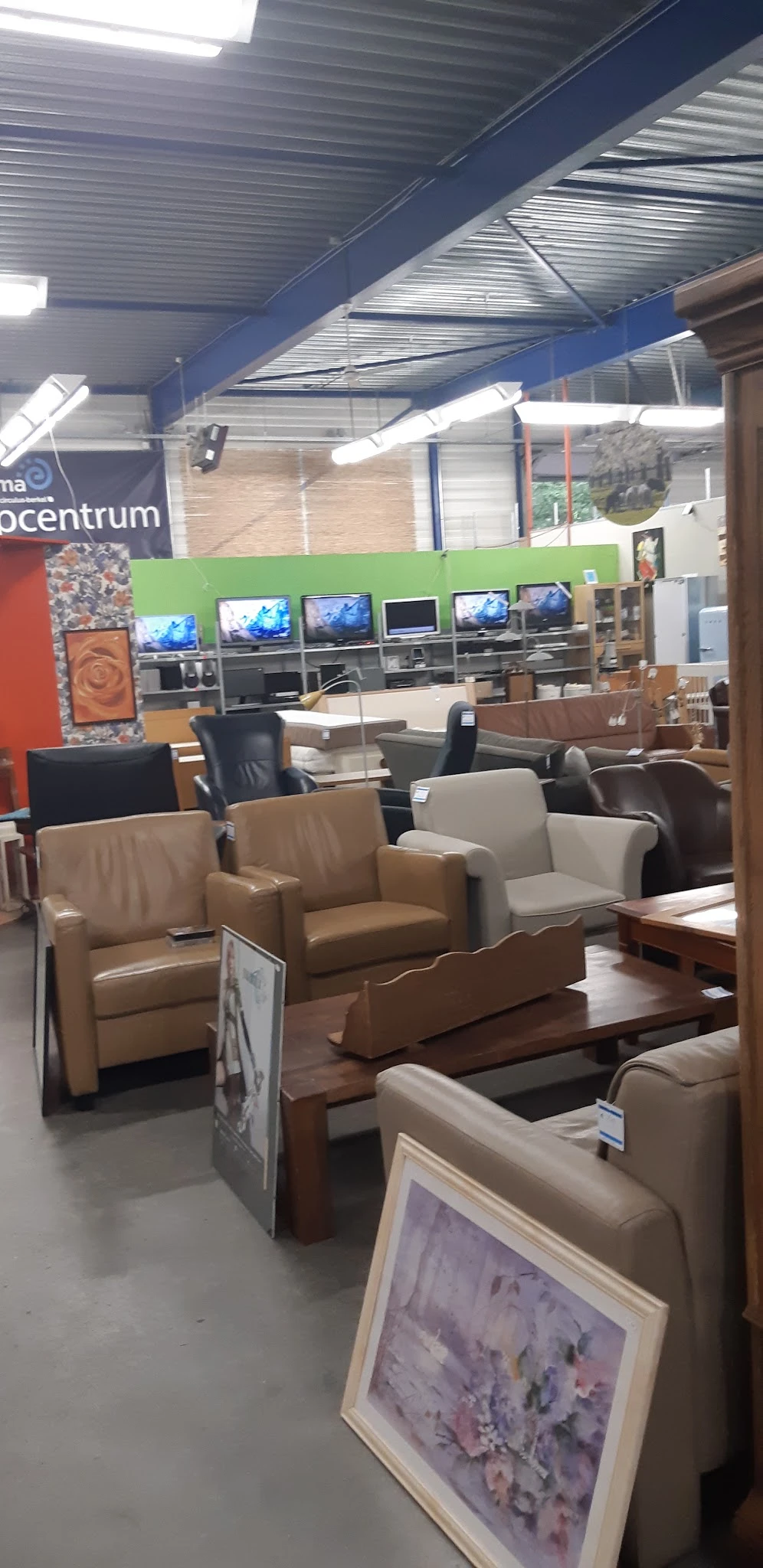 Uitgestalde meubels waaronder bruine en beige lederen fauteuils en stoelen in de winkel