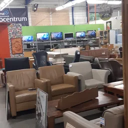 Uitgestalde meubels waaronder bruine en beige lederen fauteuils en stoelen in de winkel