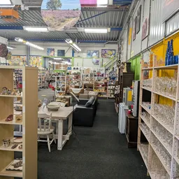 Winkelvloer van kringloopwinkel met boeken, speelgoed, meubels en overige spullen op stellingen en tafels