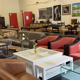 Winkelvloer met diverse meubels: bruine en rode fauteuils, grijze sofa, witte salontafel en decoratieve items
