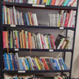 Boekenkasten met uitgestalde tweedehands boeken in verschillende kleuren op drie planken