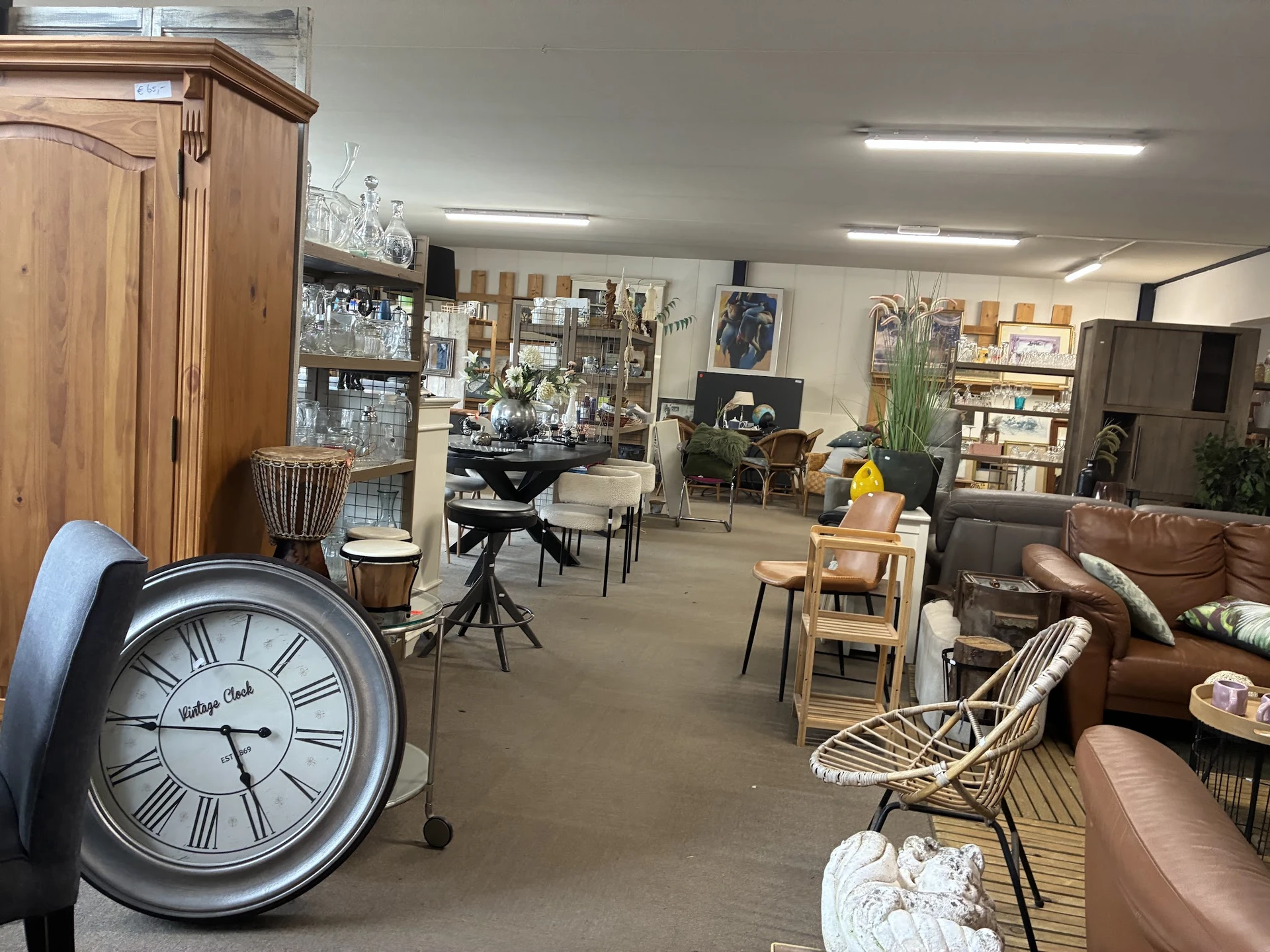 Winkelvloer van kringloopwinkel met meubels, kasten, boeken, decoratie en vintage klok op voorgrond