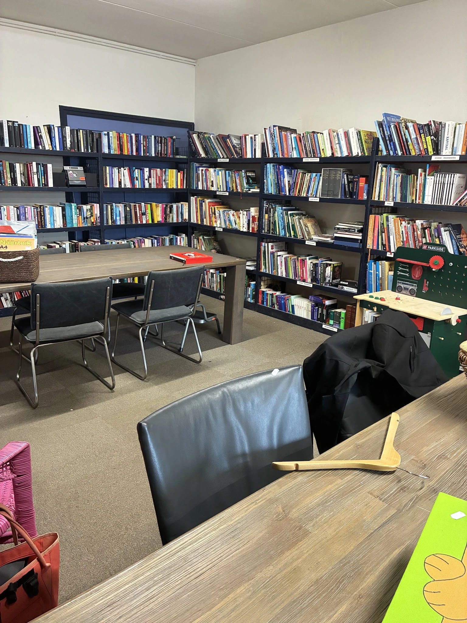 Leeszaal met boekenkasten, leestafel met stoelen en comfortabele zitplaatsen in een kringloopwinkel