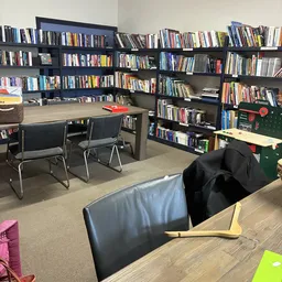 Leeszaal met boekenkasten, leestafel met stoelen en comfortabele zitplaatsen in een kringloopwinkel
