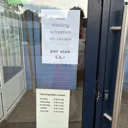 Winkelbordje met 'Alle kleding schoenen en lassen per stuk €1,-' en openingstijden