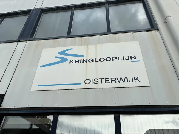 Gevel van kringloopwinkel met wit bord en blauw logo van Kringlooplijn Oisterwijk