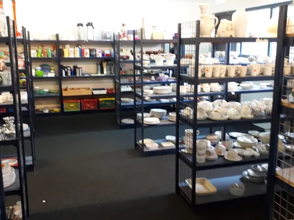 Winkelinterieur met zwarte stellingen vol witte serviesgoed en huishoudartikelen