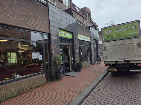 Winkelvoorgevel met groene Kringloop-bord en ingang aan Kanaalstraat, met straat en voorbijrijdende vrachtwagen