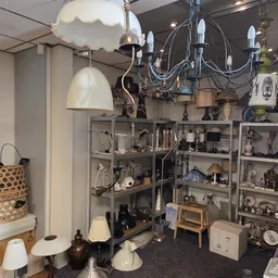 Stellingen vol met tweedehands huishoudelijke artikelen, lampen, kandelaars en decoratieve items