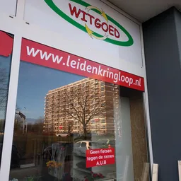 Winkelruit met website-adres www.leidenkringloop.nl, spiegeling van appartementengebouw en boom zichtbaar