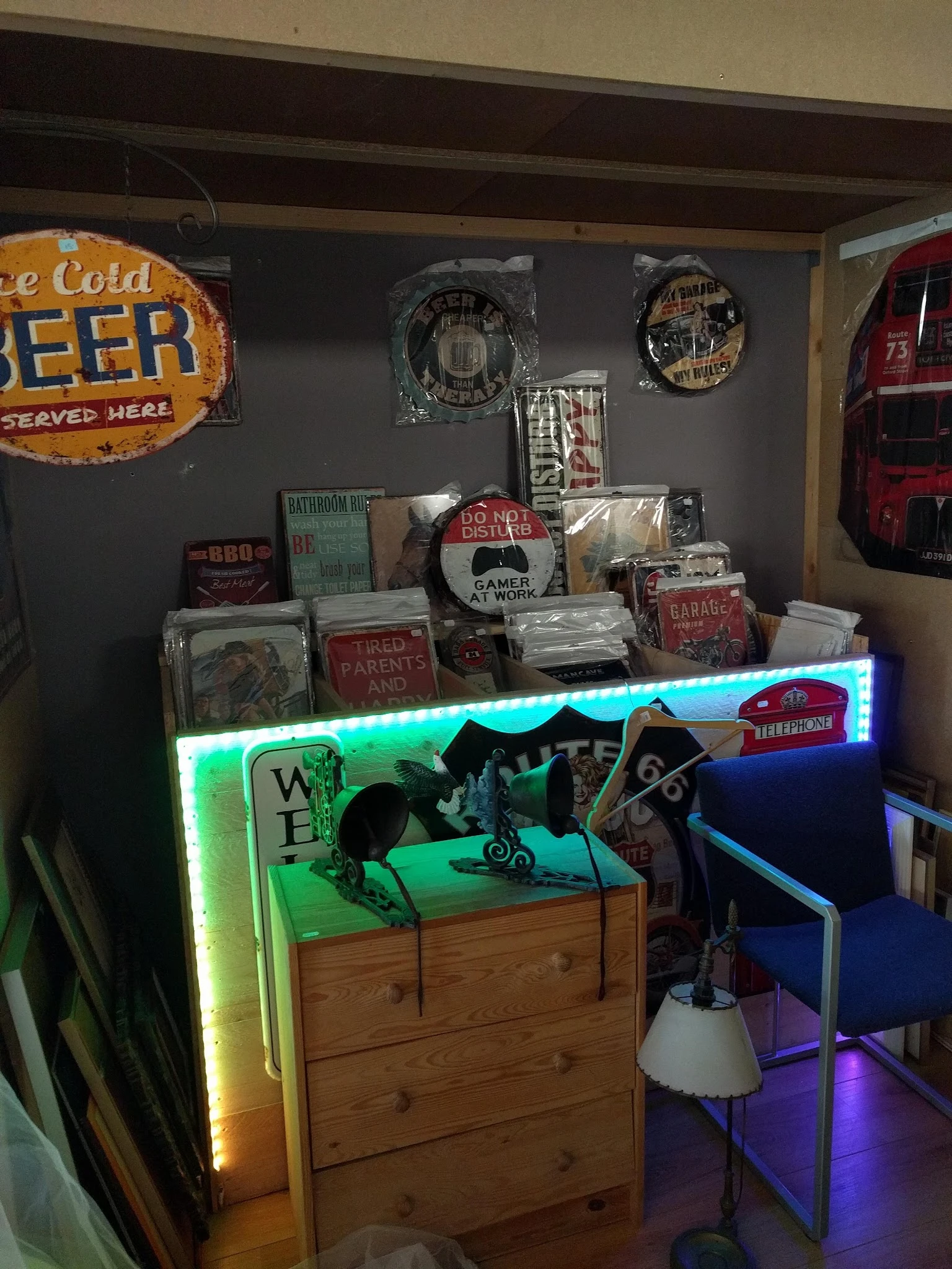 Uitgestalde vintage decoratie-items en retro borden in een kringloopwinkel met neonverlichting