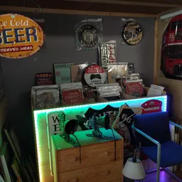 Uitgestalde vintage decoratie-items en retro borden in een kringloopwinkel met neonverlichting