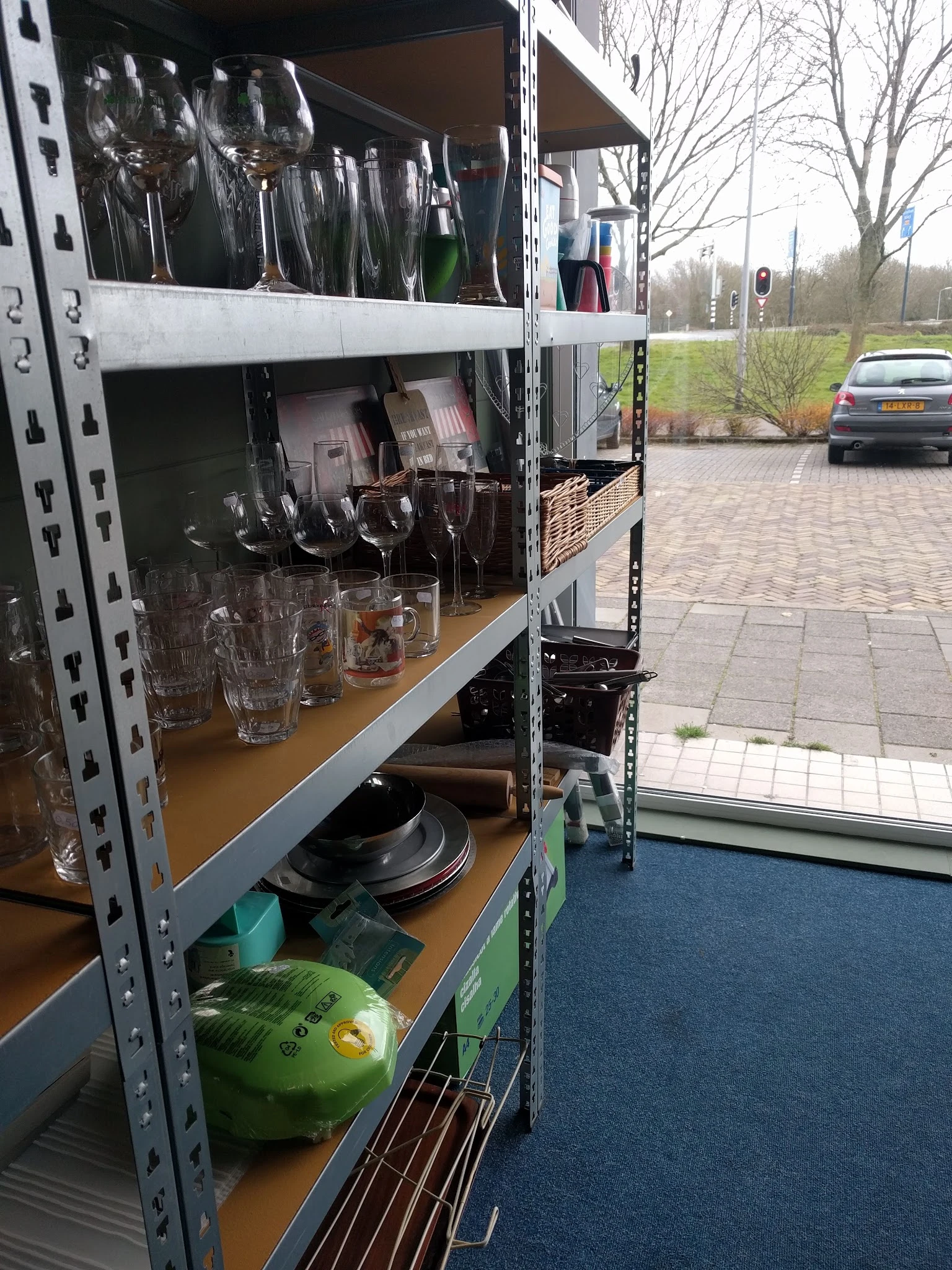 Stellingrek met glazen, borden en huishoudelijke artikelen in de kringloopwinkel