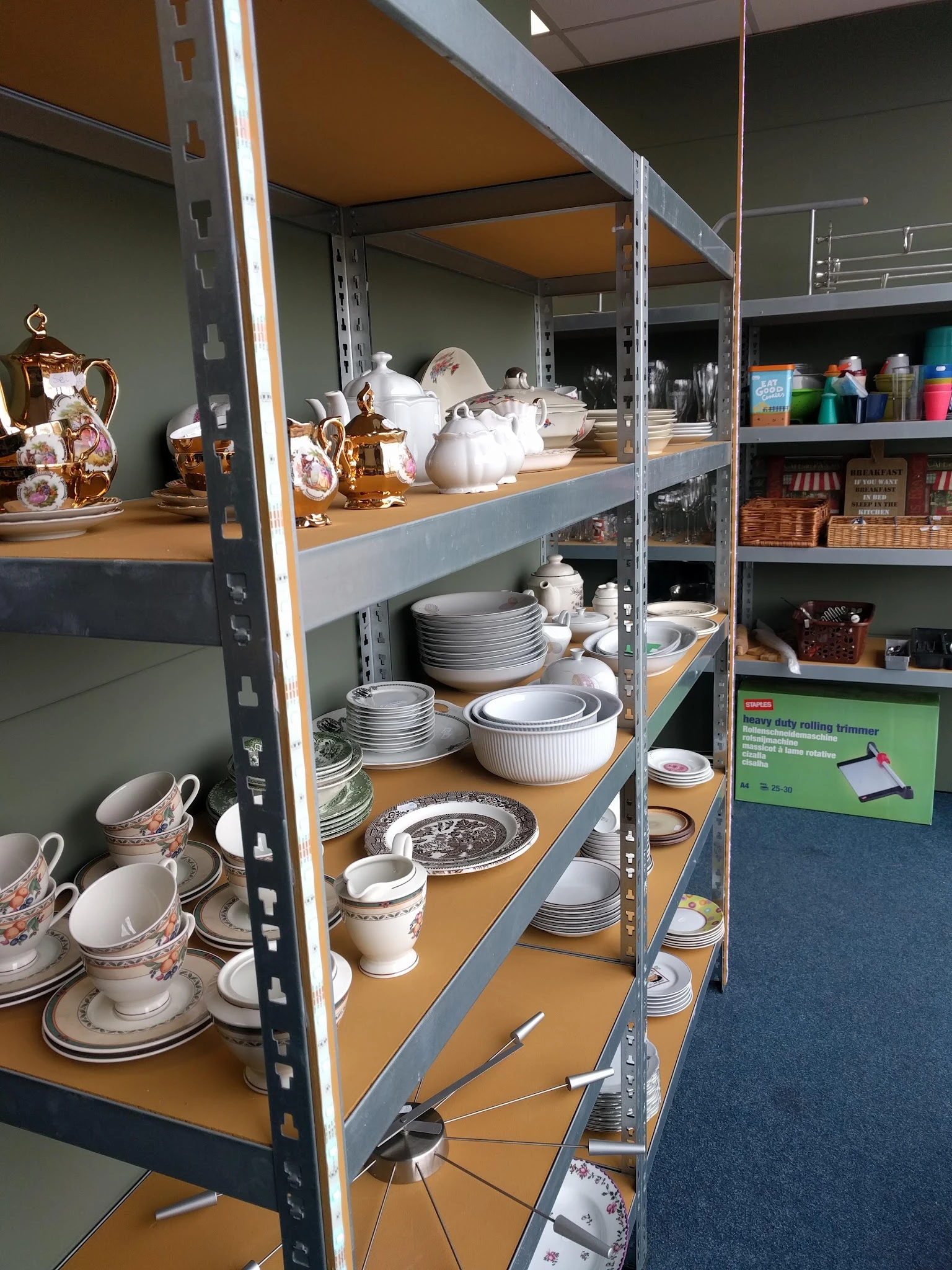 Stellingen met wit serviesgoed, borden, schalen en andere keukengerei in een kringloopwinkel