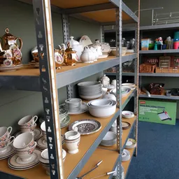 Stellingen met wit serviesgoed, borden, schalen en andere keukengerei in een kringloopwinkel
