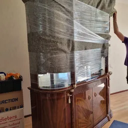 Houten vitrinekast met glazen deuren, gedeeltelijk ingepakt in plastic wrap