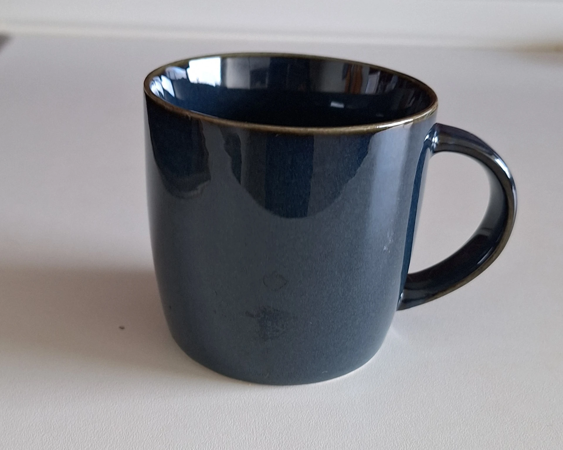 Donkerblauwe mok met gouden rand, close-up van een servies artikel