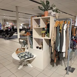 Kledingrekken en displaykasten met tweedehands kleding, accessoires en decoratie in een kringloopwinkel
