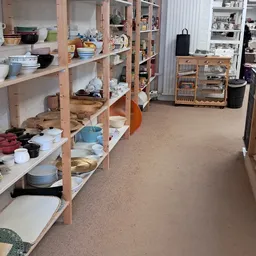 Winkelvloer met houten stellingen vol met servies, borden, kopjes en huishoudartikelen in een kringloopwinkel