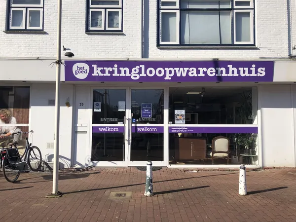 Paarse gevel van kringloopwarenhuis met grote etalage, winkelnaam duidelijk zichtbaar