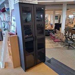 Winkelinterieur met zwarte glazen kastenwand, houten balie links, rode en zwarte stoelen en overzicht van de winkelvloer met 