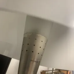 Close-up van een witte cilindervormige ventilatiebuis met gaten en tekstprint