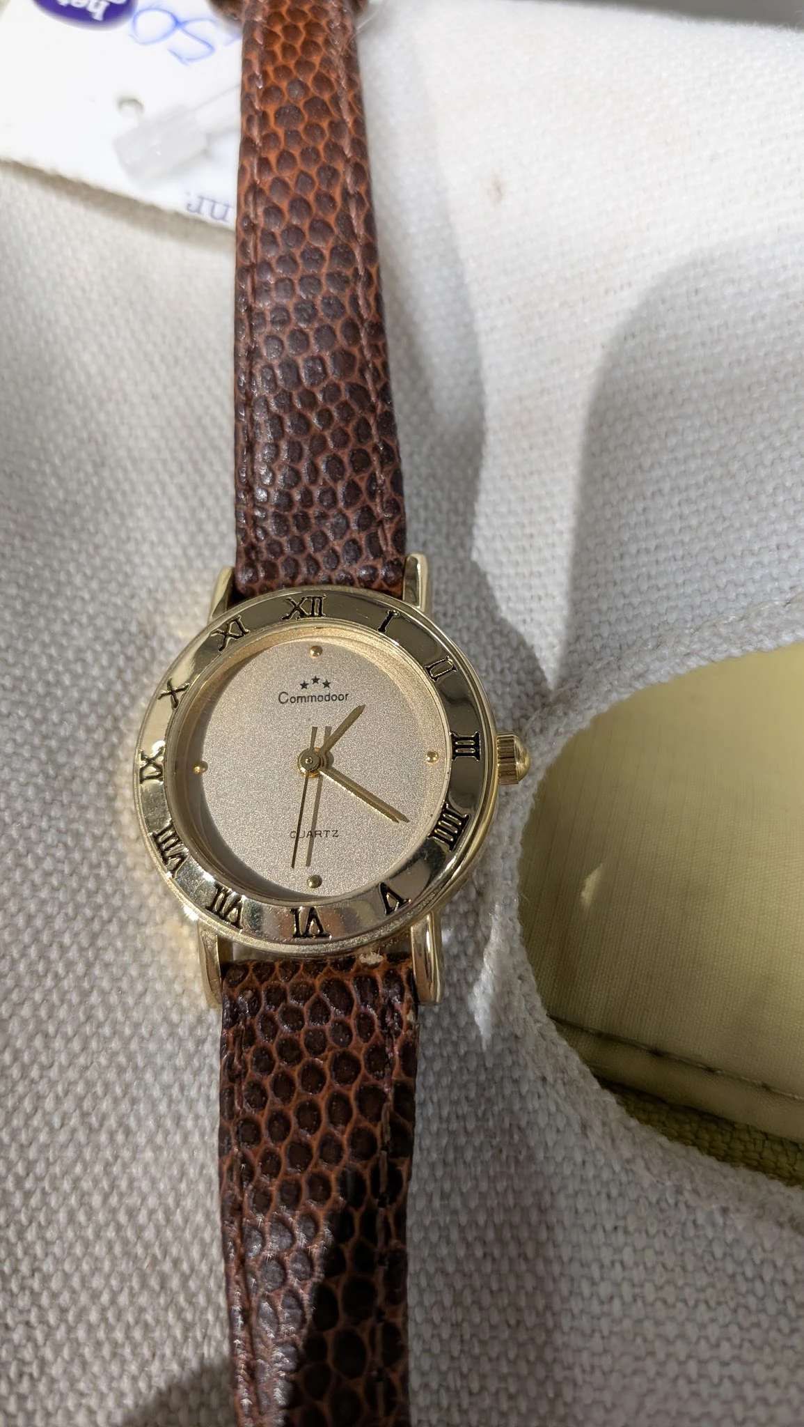 Goudkleurig horloge met bruinen leren band en Romeinse cijfers op het display