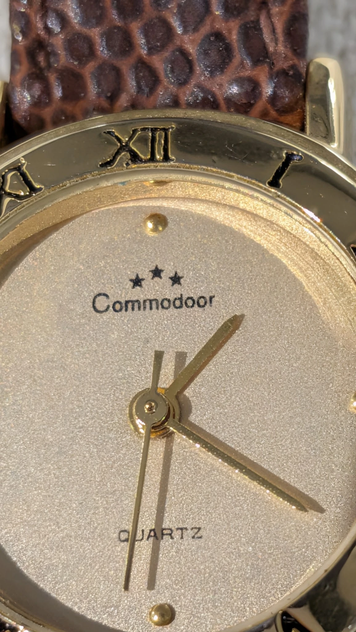 Close-up van een Commodoor klok met drie sterren en gouden wijzers op een glitterende wijzerplaat