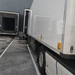 Bedrijfsbus met oplegger op parkeerterrein naast winkelgebouw