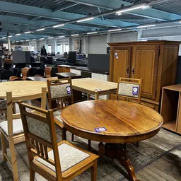 Uitgestalde meubels in de kringloopwinkel: houten tafels, stoelen en kasten
