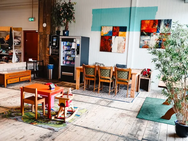 Winkelvloer met houten meubels, kunstwerken aan de wand en speelgoed, opgesteld in verschillende secties