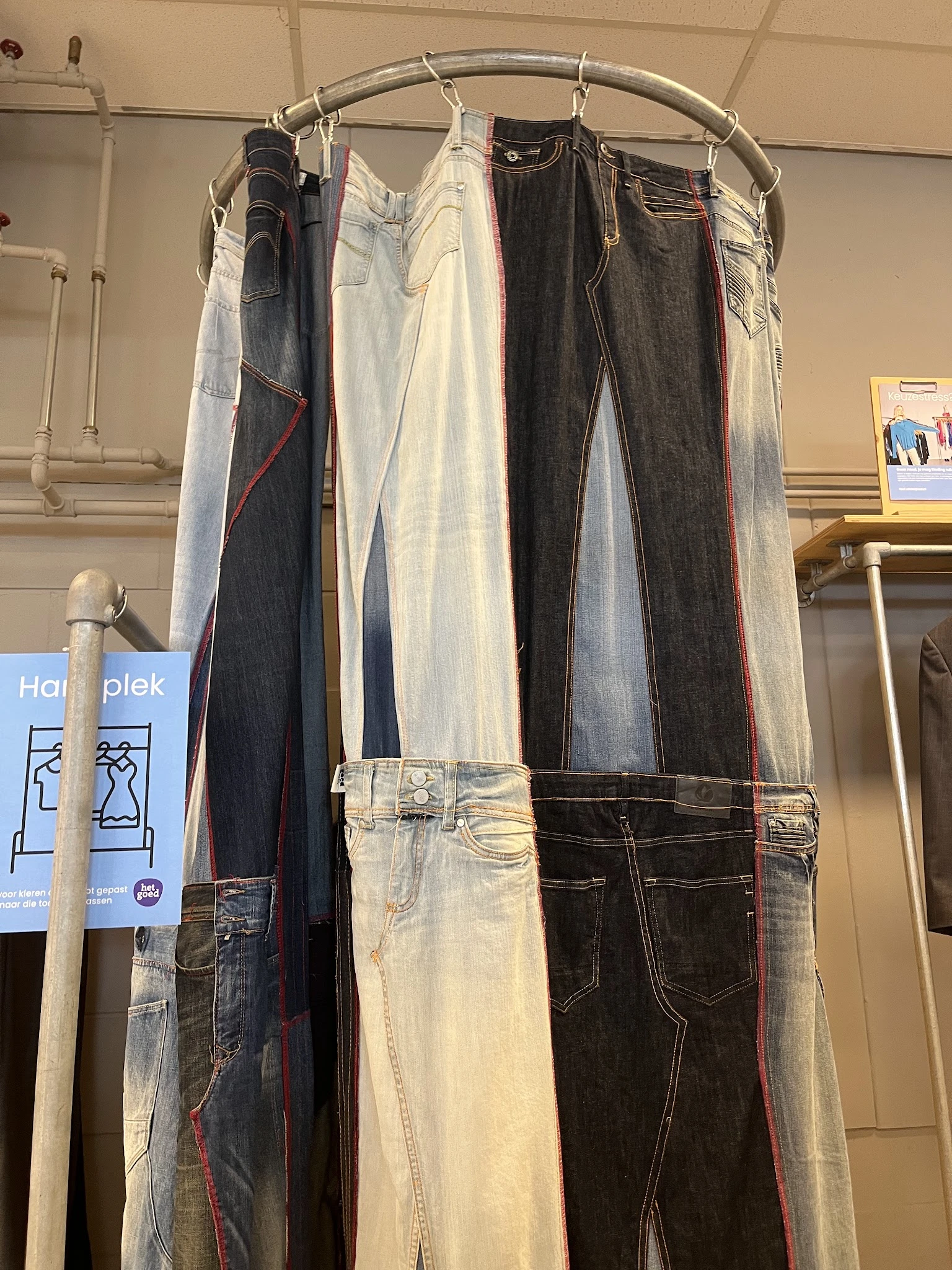 Rekken met tweedehands jeans in verschillende kleuren en wassen