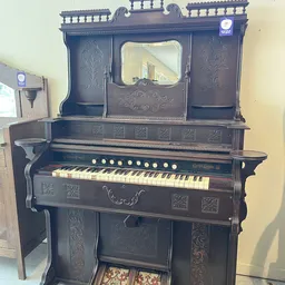 Antieke zwarte piano met decoratief snijwerk en een spiegel op het bovenwerk
