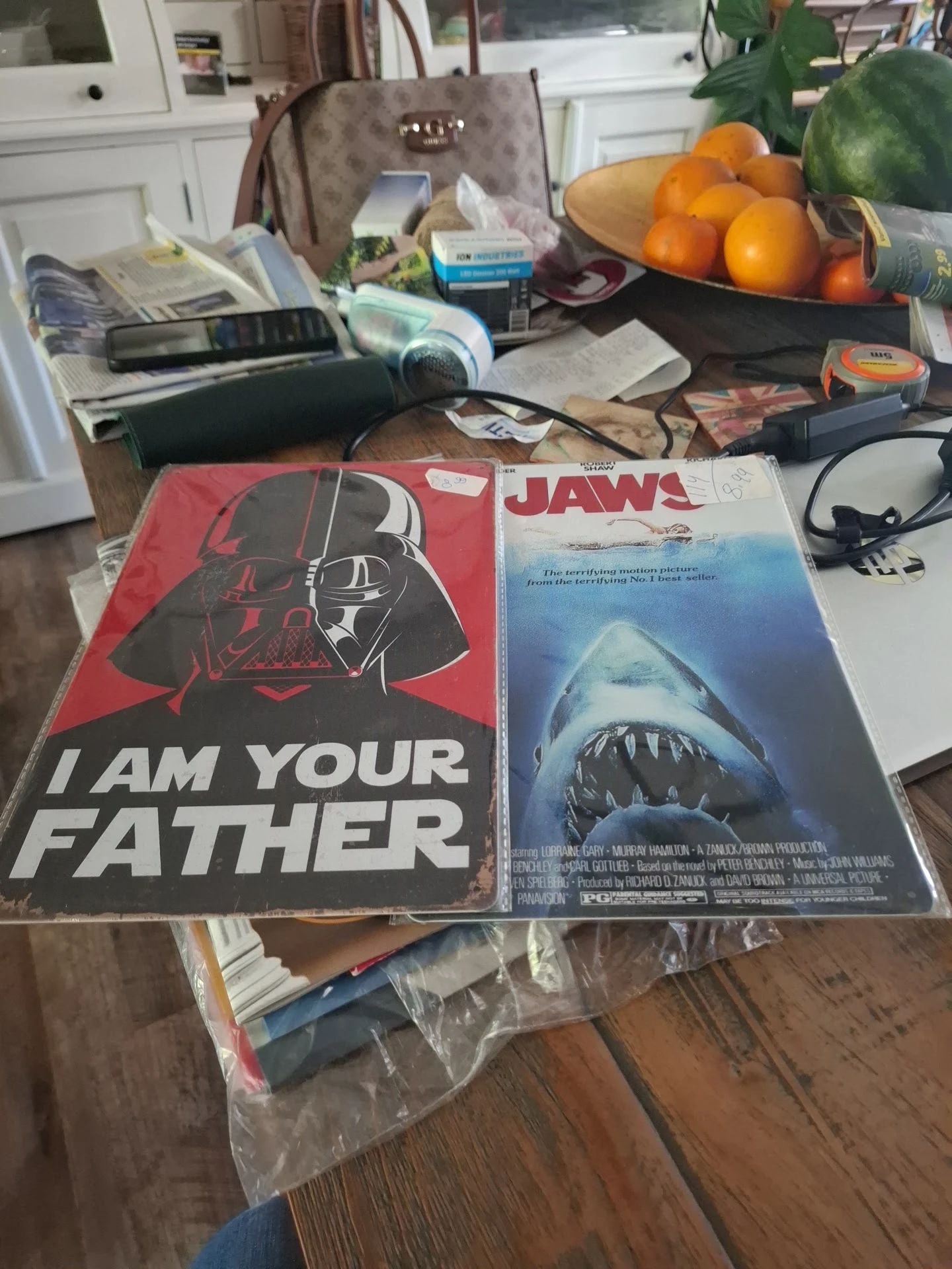 Twee filmposters op een tafel tussen andere spullen: Star Wars 'I Am Your Father' en Jaws