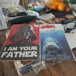 Twee filmposters op een tafel tussen andere spullen: Star Wars 'I Am Your Father' en Jaws