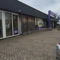 Voorgevel van kringloopwinkel met winkelruit nummer 29 en aangrenzen winkel, op bakstenen plein