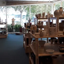 Houten tafels en rekken met aardewerk, potten en servies in de winkel