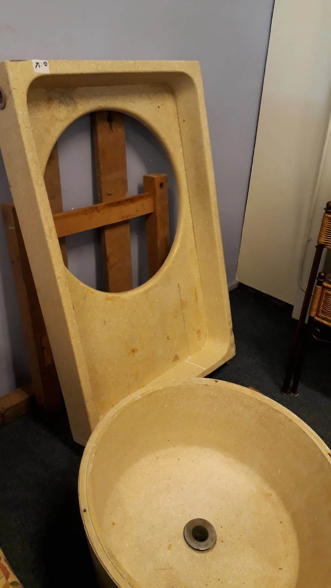 Geel kunststof stoel met gat in de rugleuning, tegen houten frame