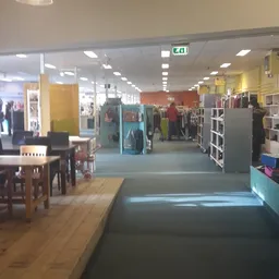 Winkelinterieur met kledingrekken, stellingen en diverse afdelingen onder fluorescerende verlichting