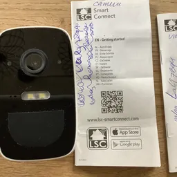 Zwarte videodeurbel met camera en instructiekaart met meertalige handleiding