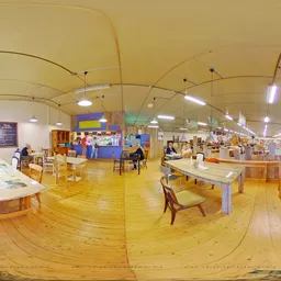 Ruim interieur van kringloopwarenhuis met houten vloer, tafels, stoelen en diverse kasten verspreid over het verkoop­oppervla