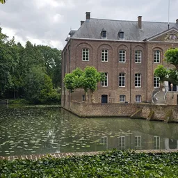 Historisch bakstenen gebouw aan water met bomen, geen winkelinterieur zichtbaar