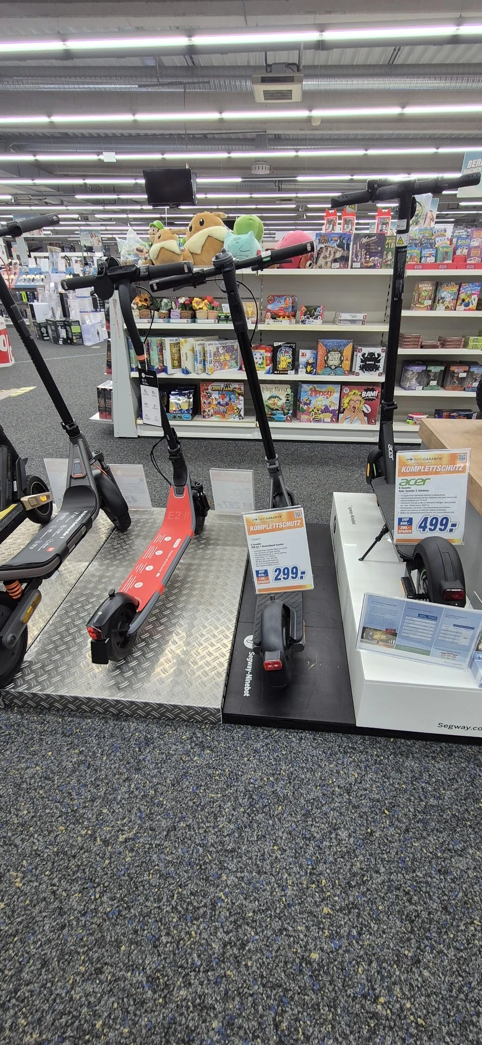 Uitstalling van elektrische stepjes en scooters met prijskaartjes in een kringloopwinkel