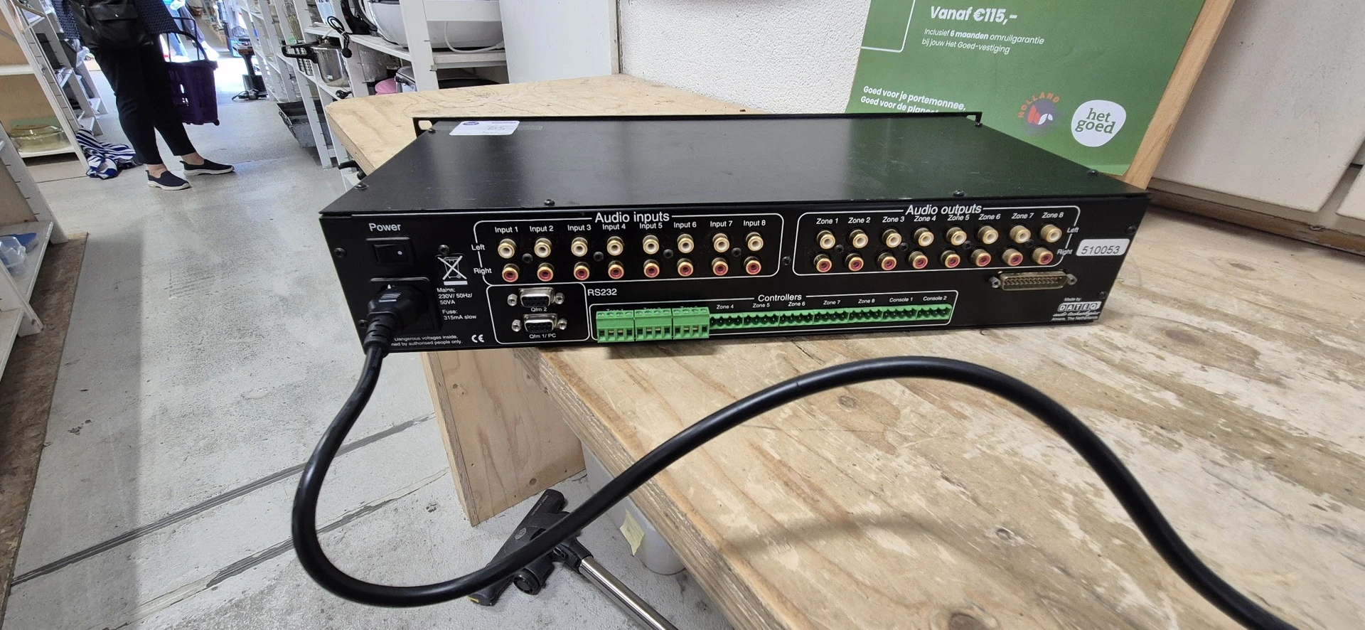 Close-up van een zwarte audioamplifier met meerdere ingangs- en uitgangaansluitingen