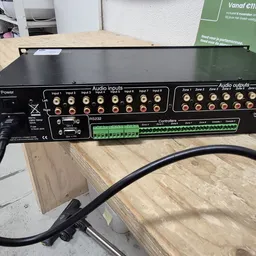 Close-up van een zwarte audioamplifier met meerdere ingangs- en uitgangaansluitingen