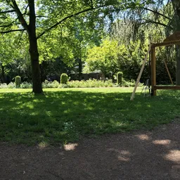 Parkachtig terrein met grasveld, bomen en een houten constructie