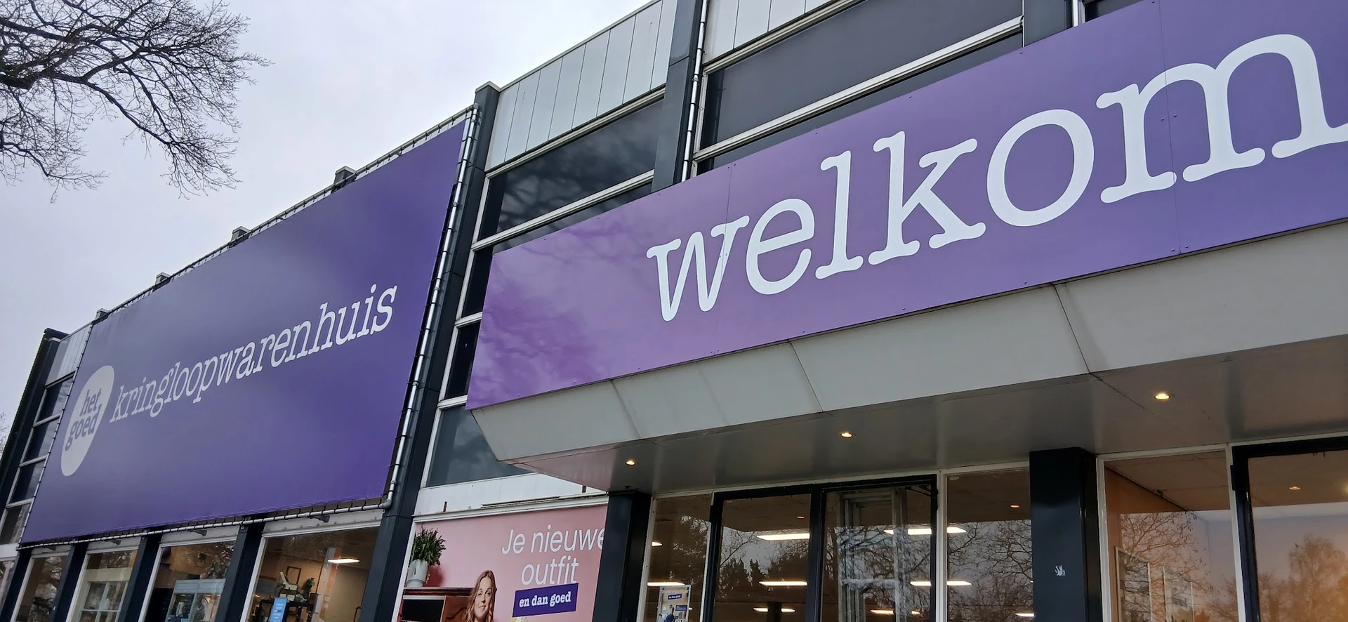 Paarse gevel van kringloopwinkel met 'welko' zichtbaar en glazen deuren