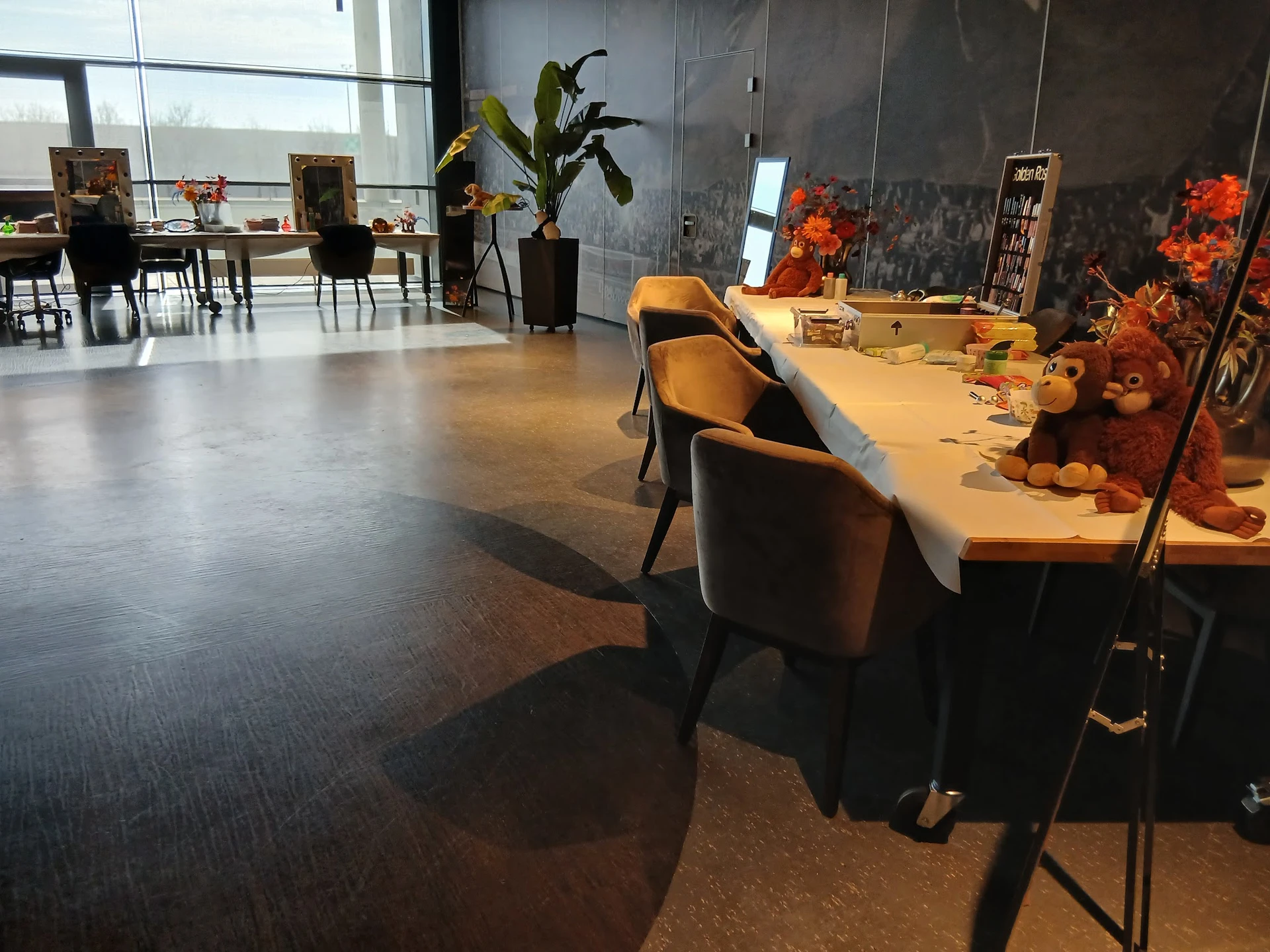 Moderne winkelinterieur met betonnen vloer, houten tafels, stoelen en decoratieve objecten, grote ramen en kunstwerk aan de w