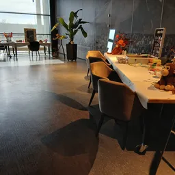 Moderne winkelinterieur met betonnen vloer, houten tafels, stoelen en decoratieve objecten, grote ramen en kunstwerk aan de w